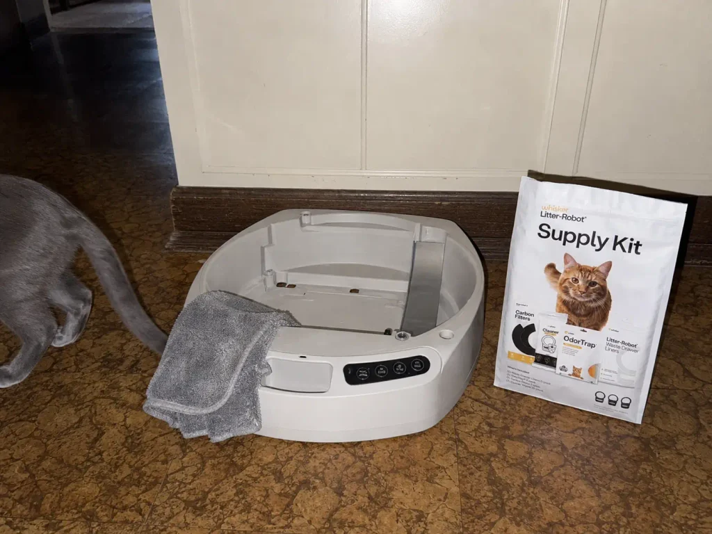 Dry cloth and cleaning wipes beside the electronic base of a self-cleaning litter box