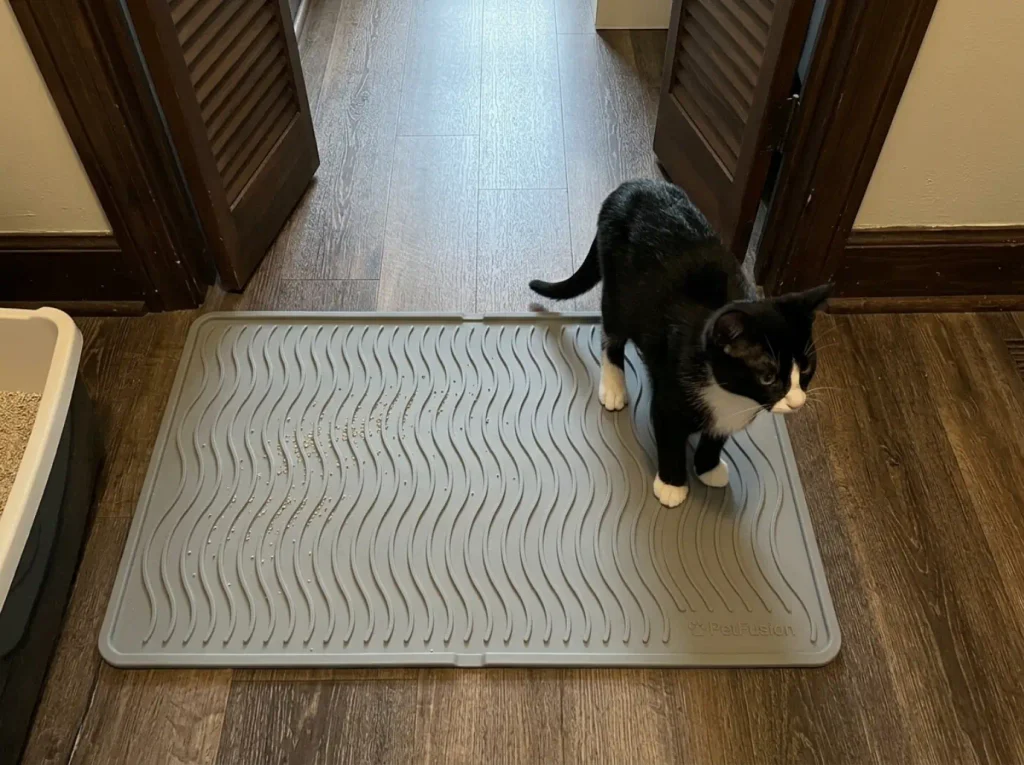 Large silicone litter mat laid across the exit zone in front of a litter box on hard flooring
