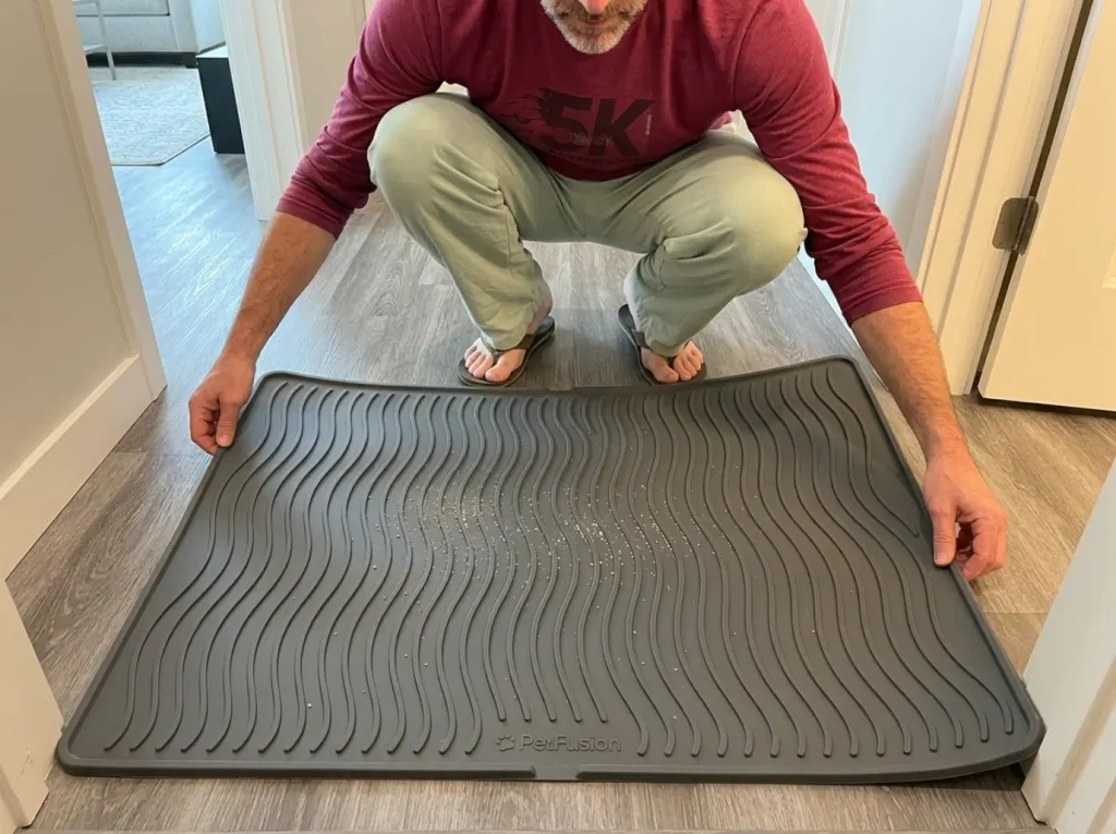 Silicone litter mat laid on rental vinyl plank flooring outside a small apartment bathroom