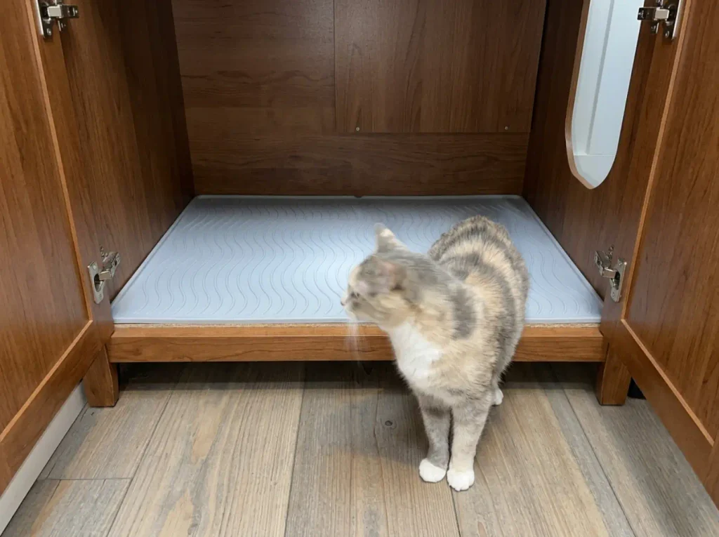 Waterproof mat laid on the floor panel inside a litter box enclosure