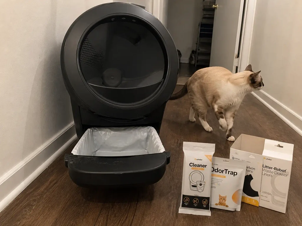 Waste drawer of an automatic litter box pulled open with a box of liners beside it