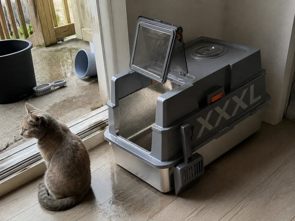 Empty stainless steel litter box drying by an open patio door after the monthly wash